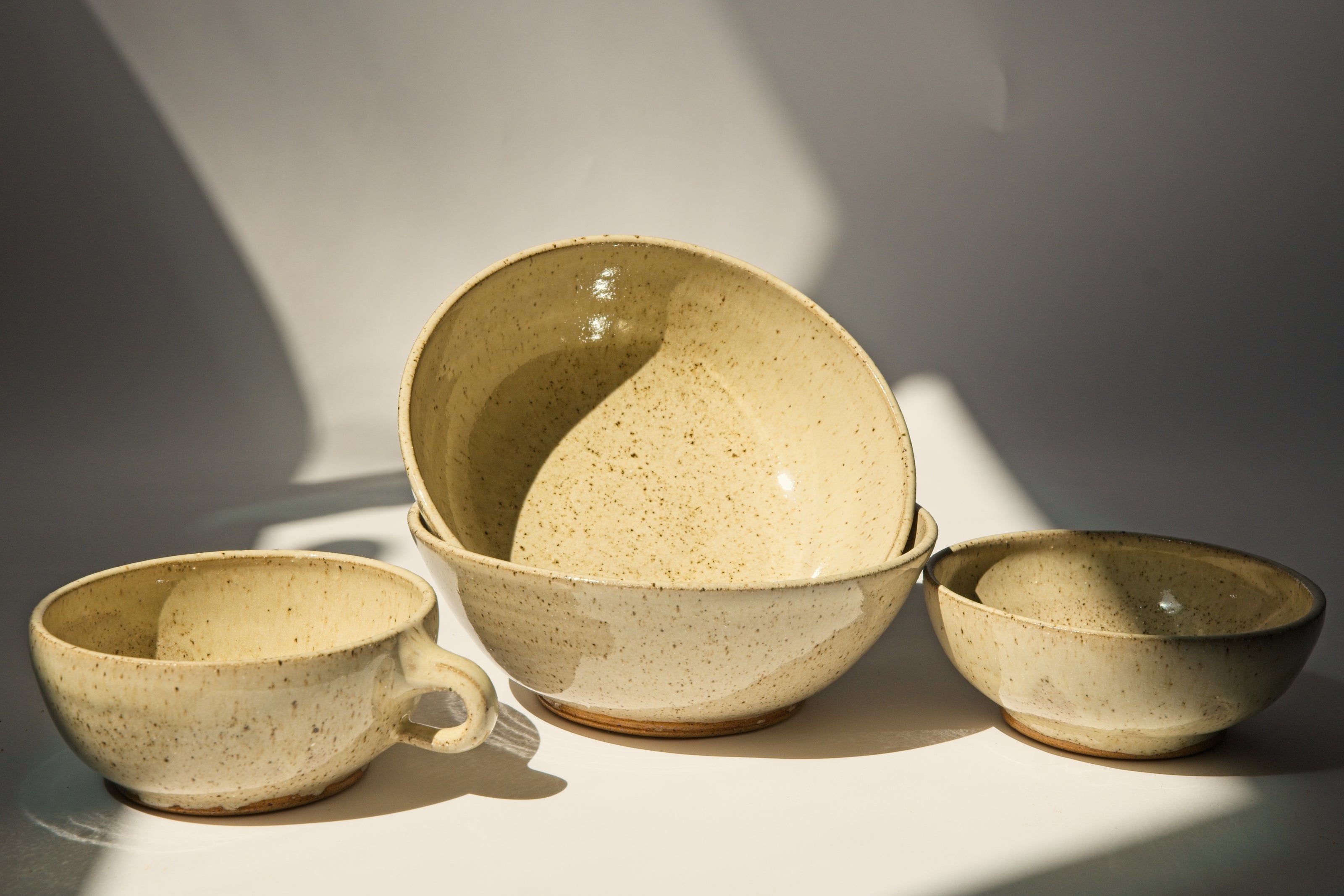 Set of ceramic bowls and espresso mug cups in beige color on a light background