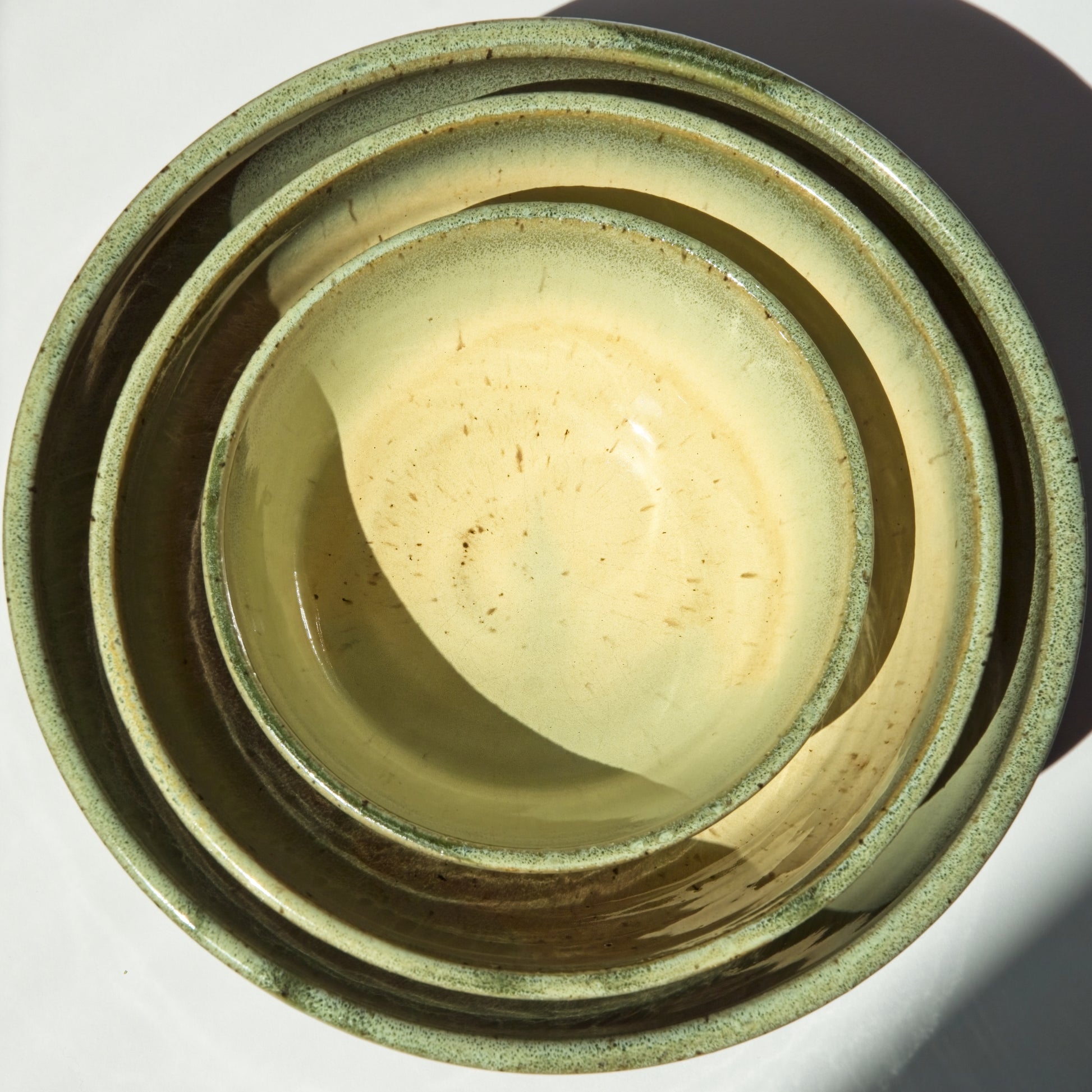 Stack of green ceramic bowls on a white background