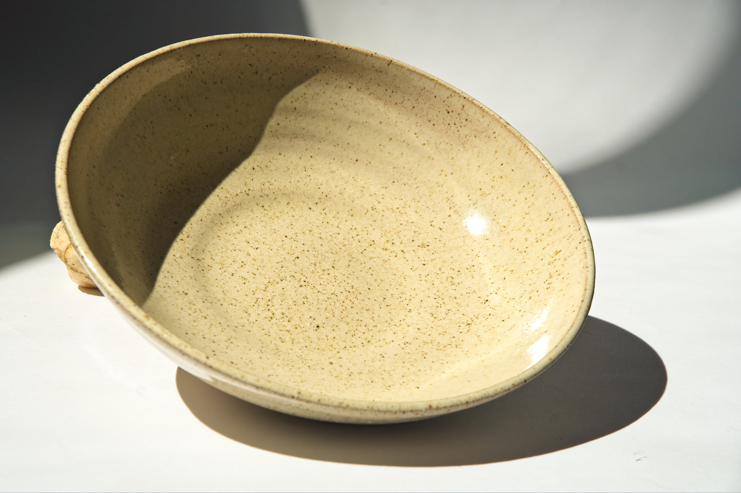 Beige ceramic bowl on a white surface with a soft shadow