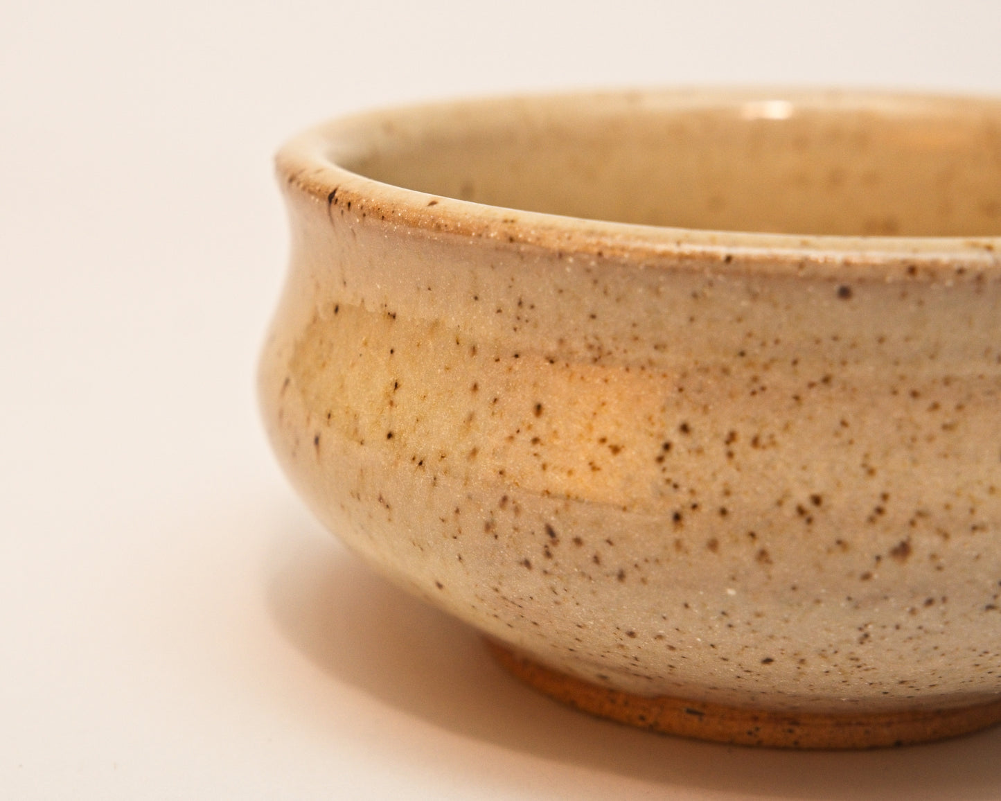 Close-up of a small ceramic copita with a speckled texture on a plain background