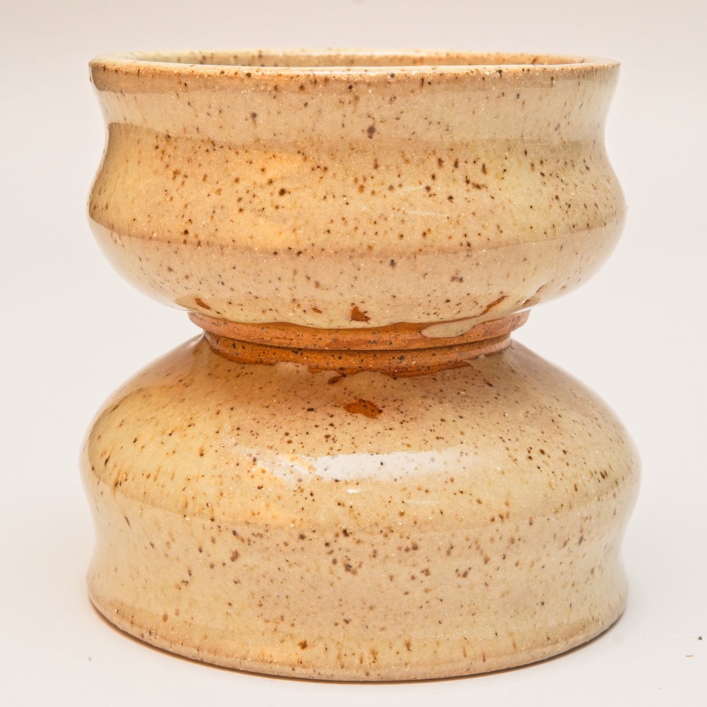Two ceramic copitas with speckled clay and a curved body, one sitting on top of the other