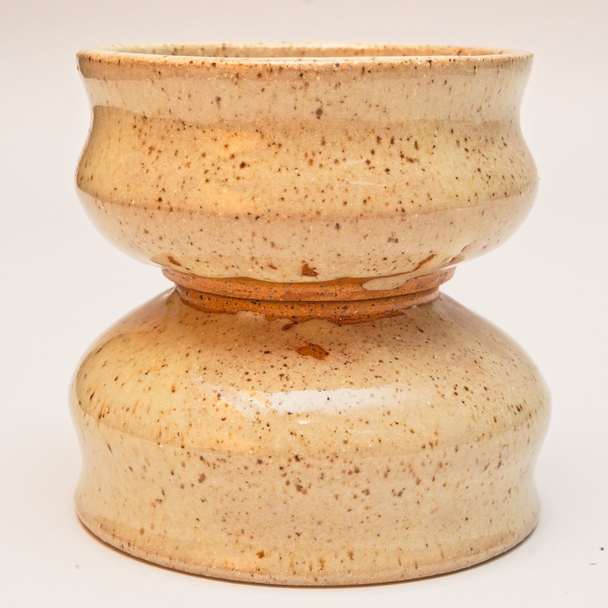 Two ceramic copitas with speckled clay and a curved body, one sitting on top of the other