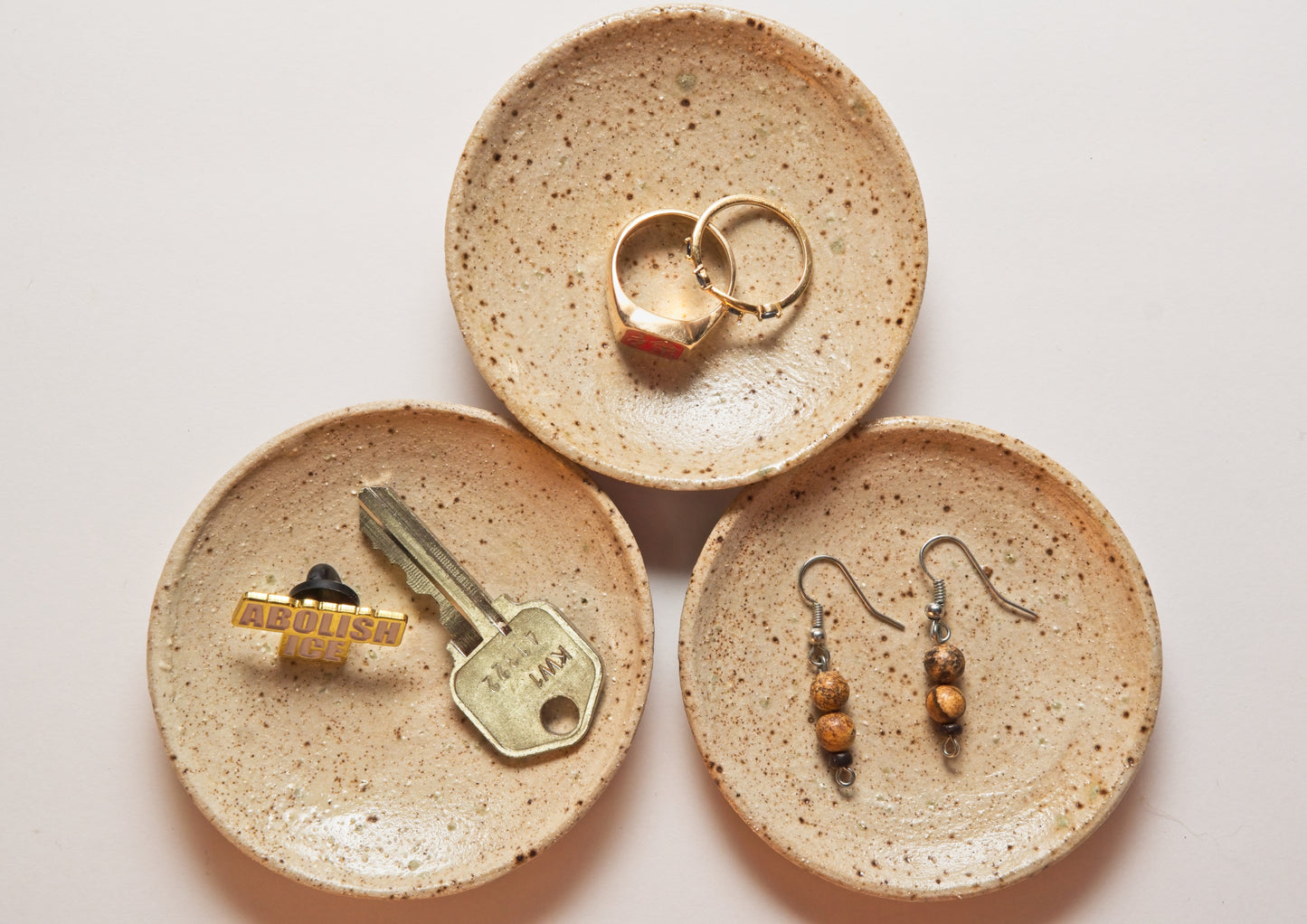 Three ceramic ring dishes with keys, rings, and earrings on a light background