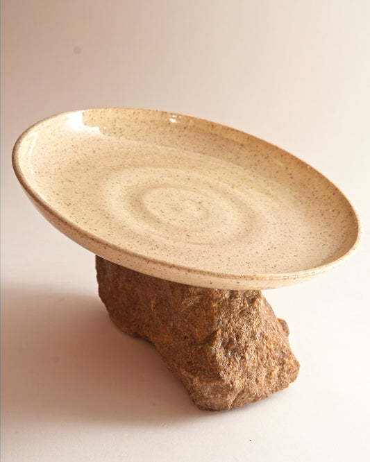 Ceramic plate sitting atop a stone base with a plain background